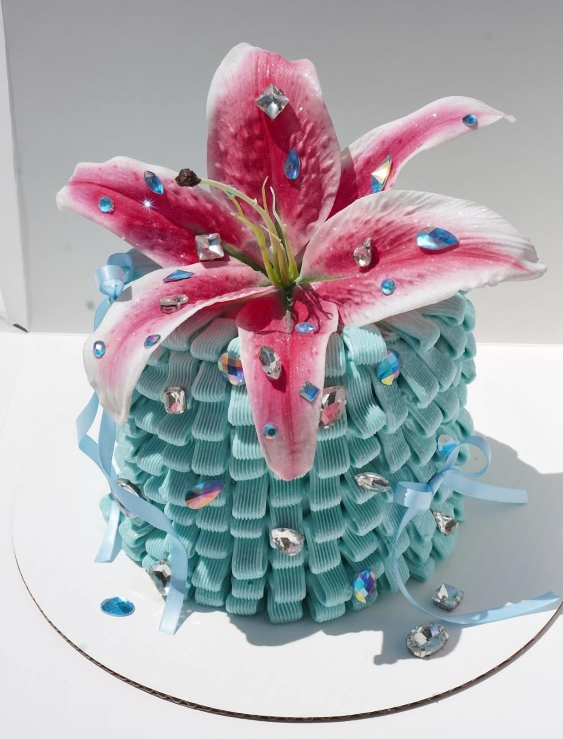 Blue lily gem cake decorated with a large pink lily, jewel embellishments and textured piping