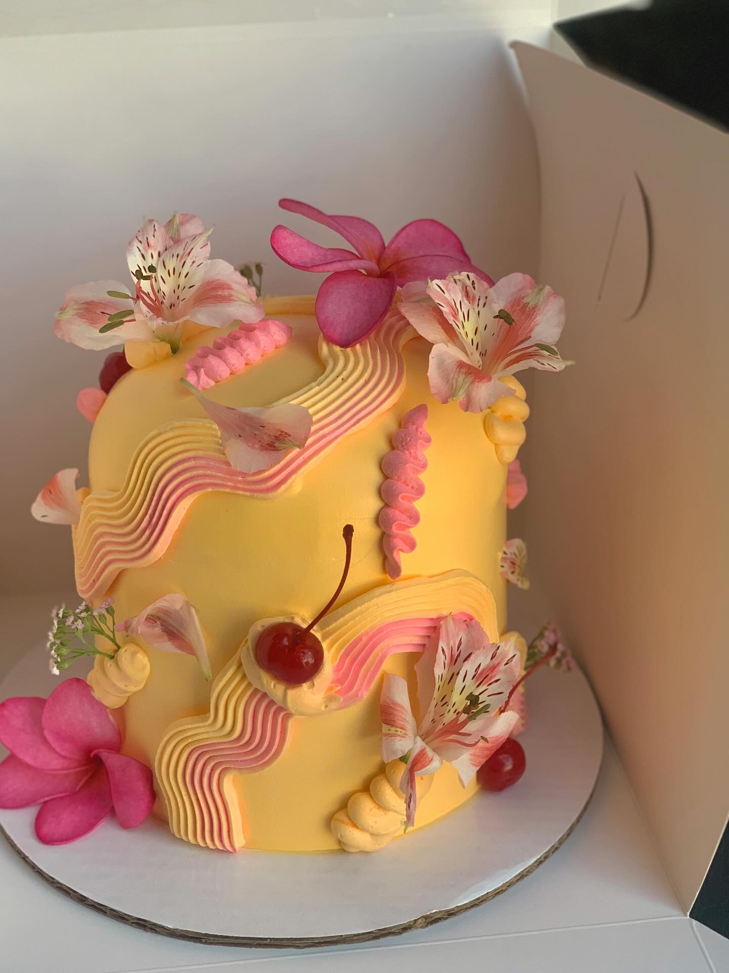 Yellow Domo cake with sculptural ridged buttercream, flowers and cherries