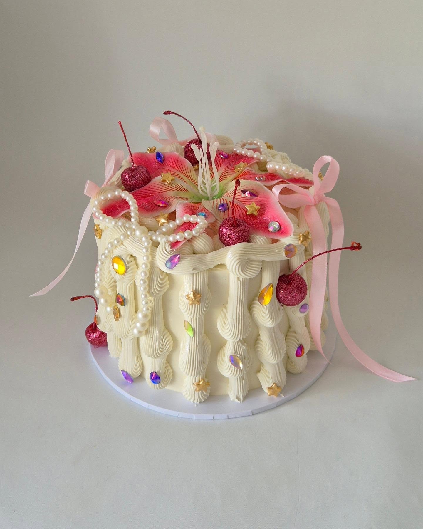 Lily gem cake decorated with a large pink lily, jewels, pearls and textured buttercream
