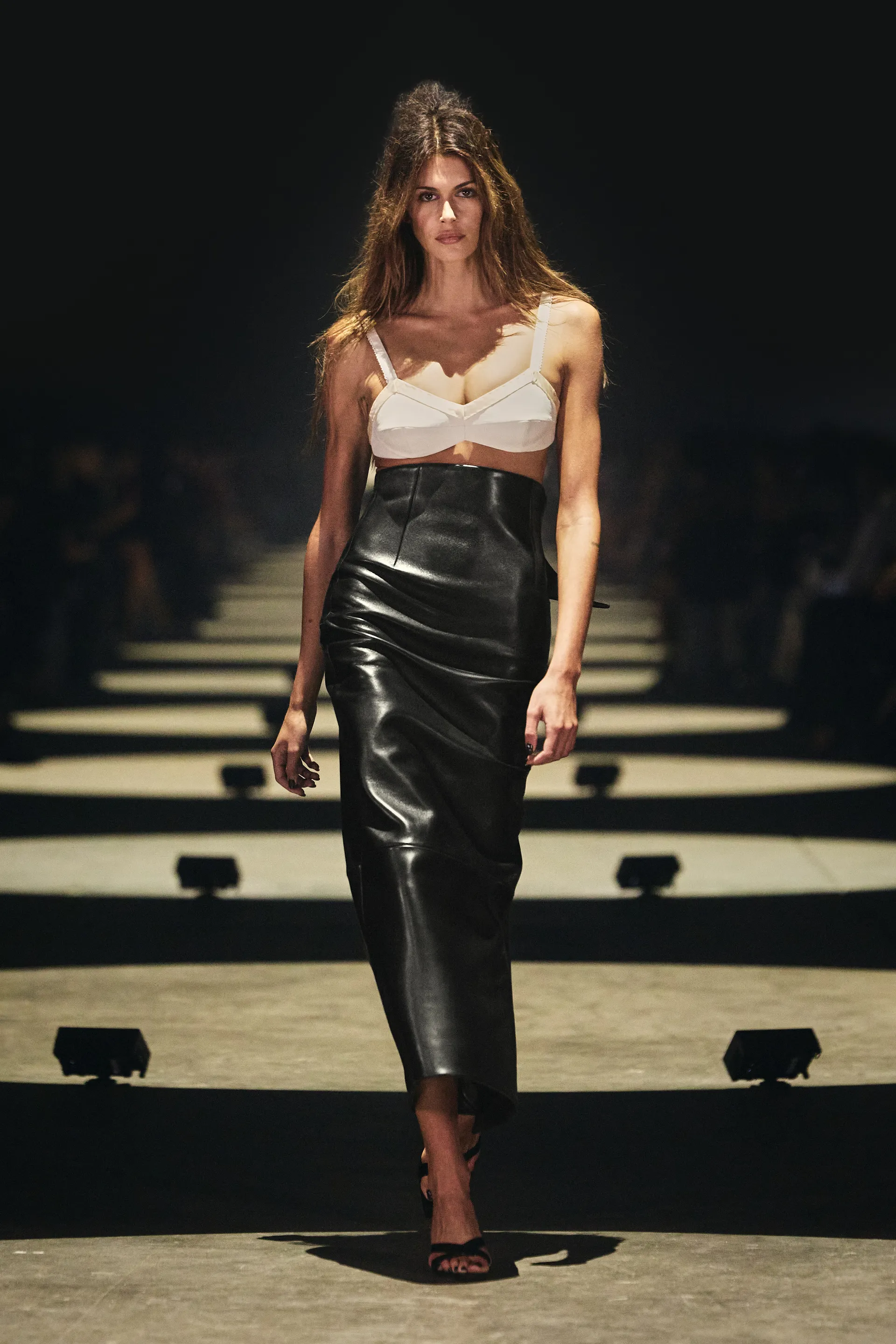 Khaite Spring 2027 white bra styled with a high-waisted black leather pencil skirt