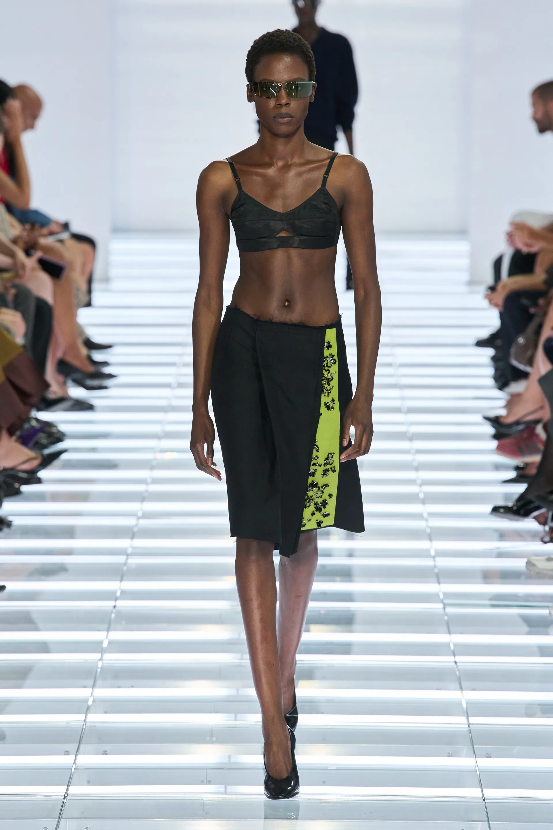 Prada Spring 2027 black bra styled with a dark skirt featuring green detailing