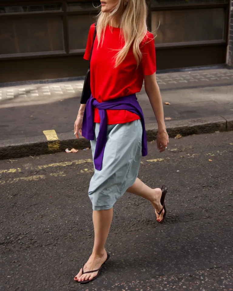 Red street style outfit styled with a purple knit tied around the waist